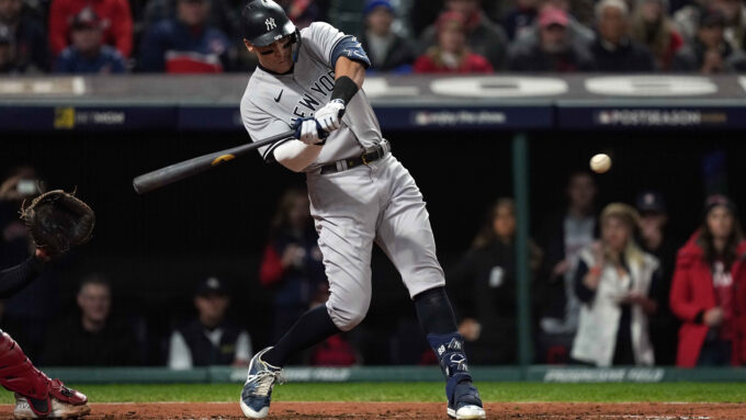 A photo of Aaron Judge swinging at a baseball with spectators out of focus in the background.