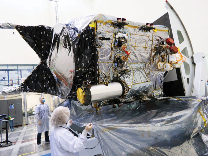 Picture of Psyche spacecraft in the clean room at NASA with scientists working on it.