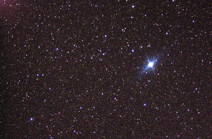 Canopus shines as a blue star. Many other smaller stars shine against the black background of space.