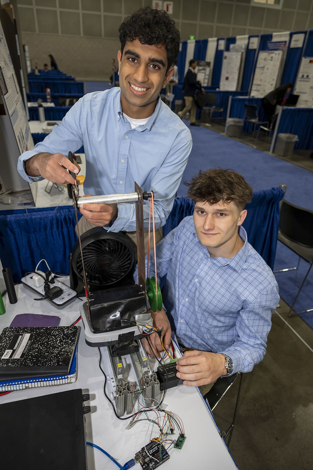 a photo of Vishnu Angiras and Misha Mishechkin and the motorized cylinder they built for their project