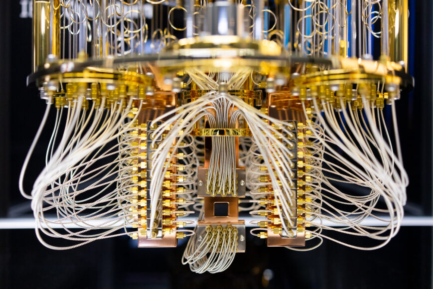 a circular structure with a shiny gold metal supports and silvery white wires runing throughout - it almost looks like a chandelier. At the very bottom there is a dark rectangle that all the wires seem to connect to, the quantum-processing chip.