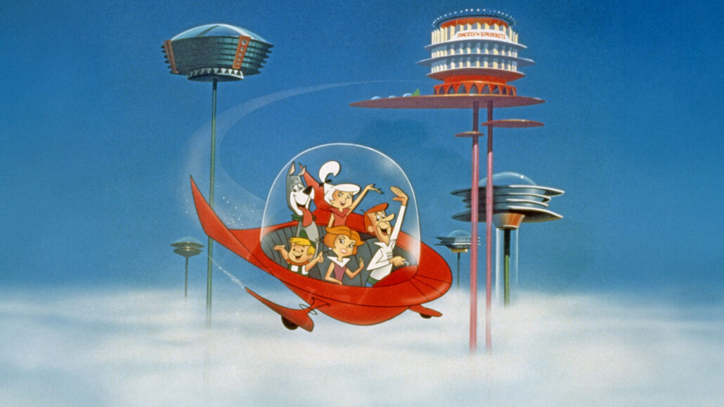 The four Jetsons and their dog sit under the glass dome of a red flying car. They float above white clouds. In the background, futuristic buildings rise above the cloud layer on beams.