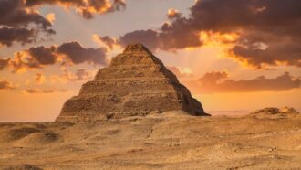 Egyptian King Djoser's pyramid rises above a sandy landscape, while sun-<a href=