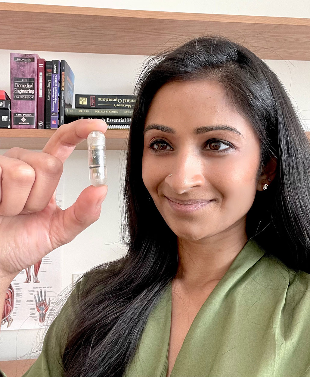 a woman holding a pill prototype up to the camera