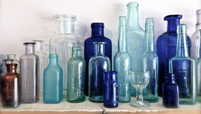 assorted glass bottles of different sizes, shapes and colors on a shelf