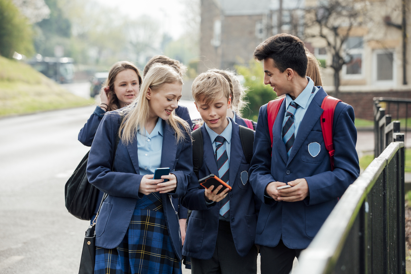 Group of teenage students walking home from school together wearing school uniforms