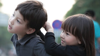 A young child pulls the hair of another child.