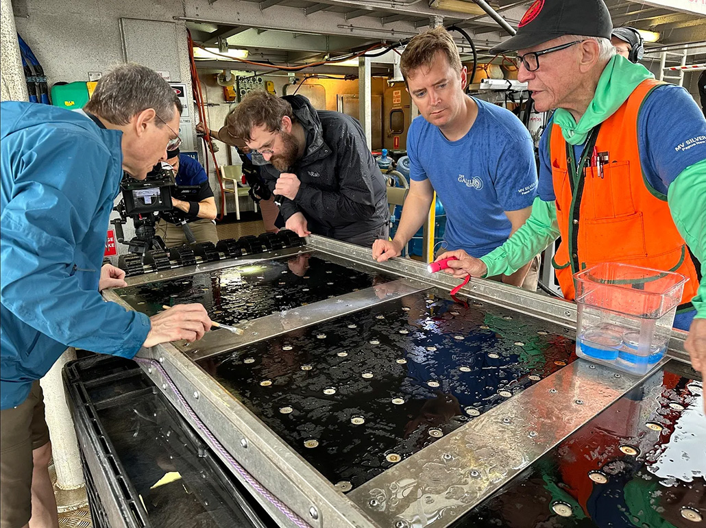 a photo of several scientists carefully examing a magnetic sled