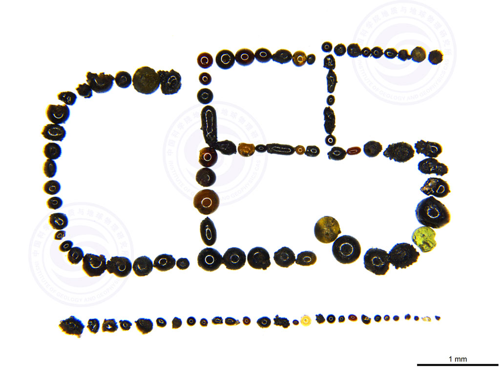 Rounded dark brown, black, and yellow glass beads brought back by the Chang’e-5 mission. Here, they’ve been arranged to spell out an abbreviation for that mission (CE5).