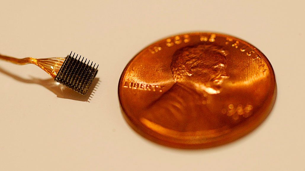 a teeny microelectrode shown next to a penny for scale, the entire array is smaller than Abraham Lincoln's face