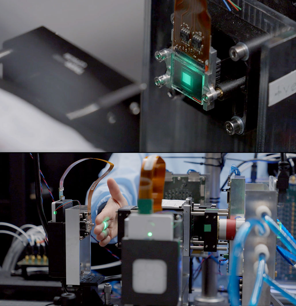 a composite of two horizontal images stacked on each other, the top image shows a computer chip with green LEDS shining on it, the bottom image shows the computer set up with a researcher inserting their hand to block the light to a chip