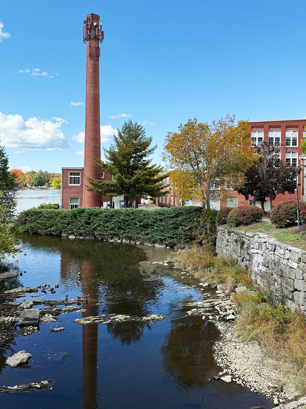 a photo of a building next to a canal, and a brown cell phone tower 