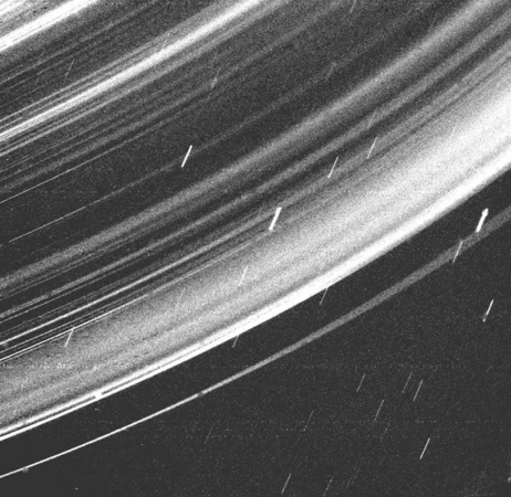 a black, white, and gray image of a section of Uranus's rings streaked with background stars (small white diagonal lines)