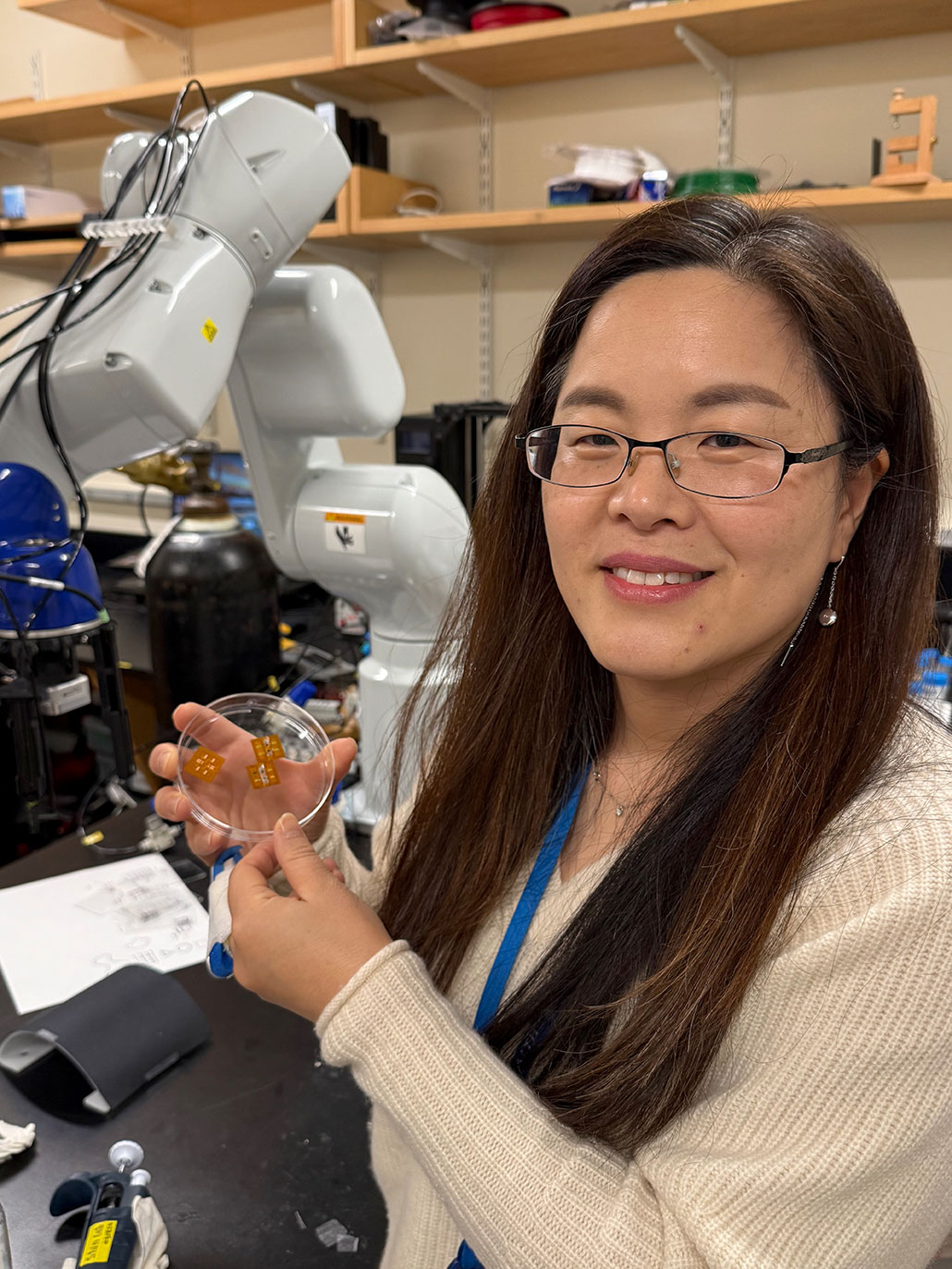 Sy Ryon Shin in her lab, smiling and holding a petri dish with tiny chips.