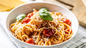 Plate with cooked spaghetti in tomato sauce, parmesan cheese and basil